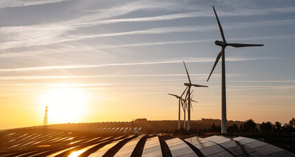 Wind turbines and solar panels seen with a sunset.