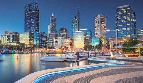 View of the colorful Perth cityscape from a walkway looking over a river.