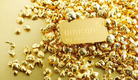A gold plate labeled Umicore on a pile of gold nuggets.