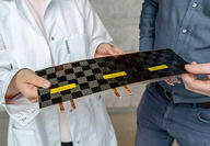 Researchers holding experimental carbon fiber battery cells.