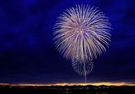 Brilliant firework display with the horizon lit by a line of the sunset.