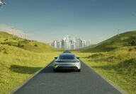 Rendering of an EV driving through wind turbines toward a city.