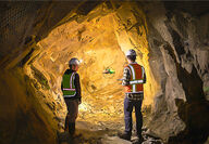 Two students in hard hats fly a drone in an underground mine.