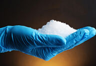 Gloved hand holding lithium hydroxide.