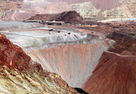 Inside the pit of a copper mine with hues of red, grey, and pink.