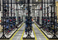 Three rows of columns on steel framework with connecting pipes in a warehouse.