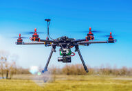 A large six-rotor drone hovering over a field.