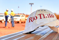 Rio Tinto logo on a hard hat with two workers in the background.