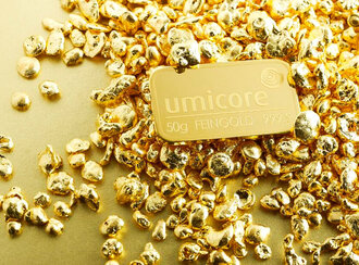 A gold plate labeled Umicore on a pile of gold nuggets.
